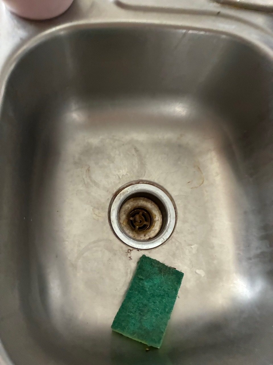 Stained, grimy stainless kitchen sink before a move-out clean